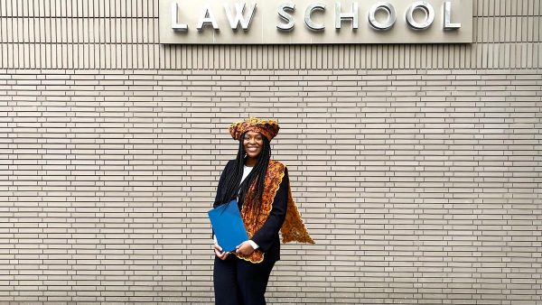Winny voor een muur met het woord Law School en haar diploma in haar handen
